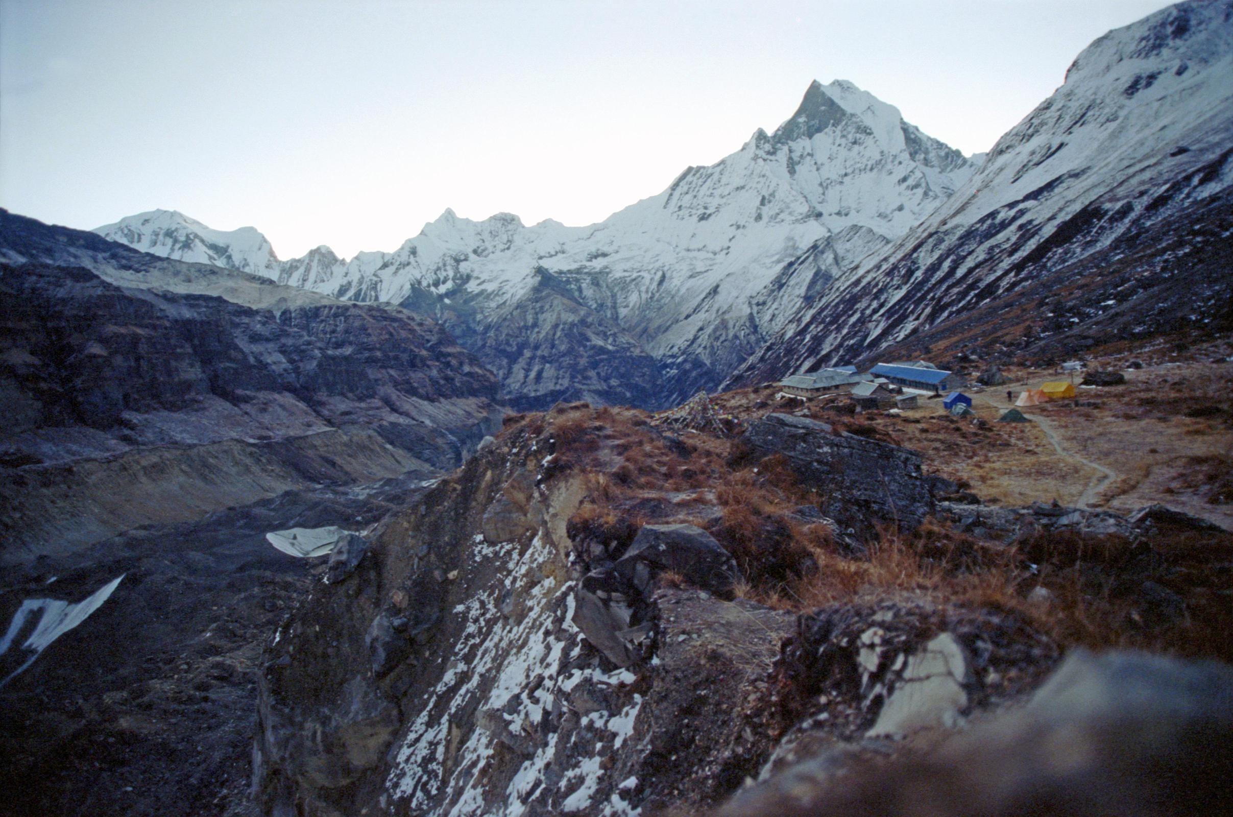 201 Annapurna Base Camp Before Sunrise - Annapurna III,  Gabelhorn, Machapuchare Annapurna Sanctuary Base Camp is a collection of stone huts surrounded by mountains and glaciers at around 4130m. This was the site of Chris Boningtons Base Camp for the 1970 British expedition that completed the first ascent of the Annapurna South Face. I was up early and walked in the -1C clear weather for ten minutes to the monument hill. Before the sun started rising, I looked back to the east of Annapurna Sanctuary Base Camp to see the ridge connecting Annapurna III (7555m) to Gandharva Chuli (Gabelhorn, 6248m) to Machapuchare (6993m).